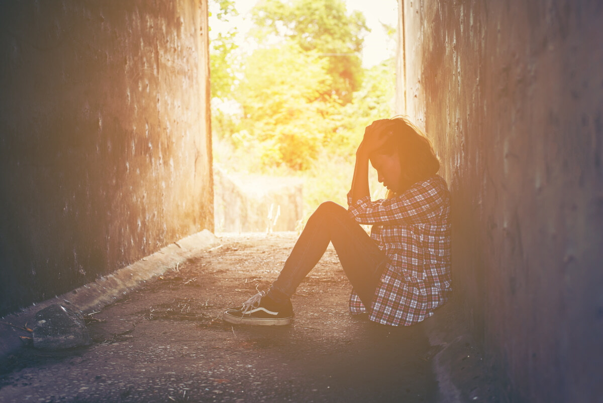 Picture of troubled lone girl sitting alone in an alley.