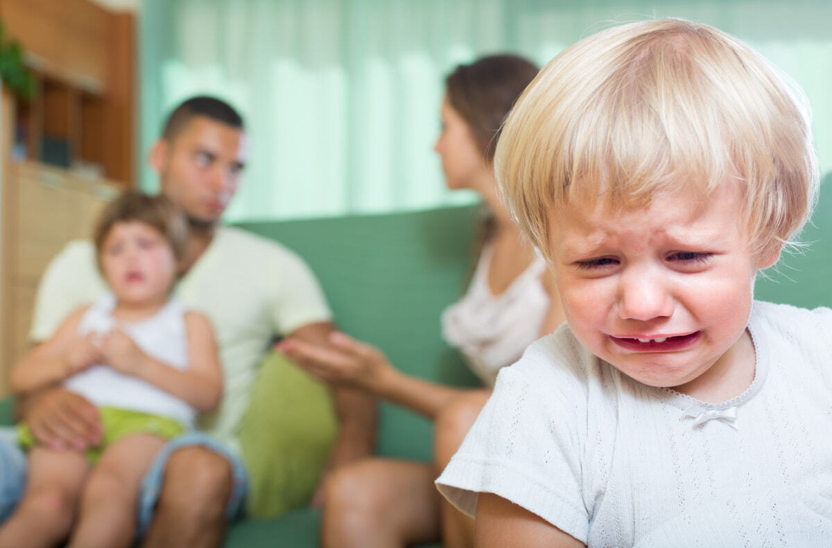 Picture of parents arguing in the background while little children crying in the front.